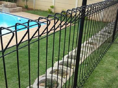 Black roll top fencing as swimming pool fence for a house.