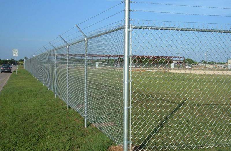 Galvanized chain link security fence with barb wire toppings.