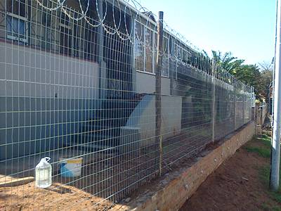 Flat wrap razor wire increases security of common residential welded wire fence.