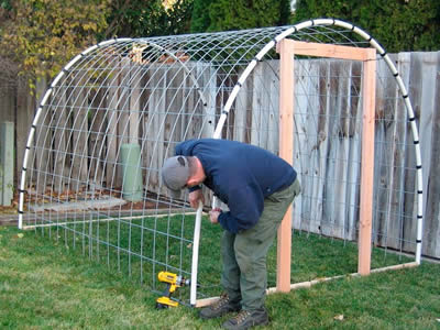 A worker is building the greenhouse by welded wire mesh.