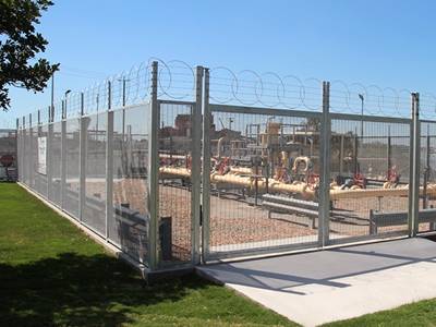 Welded wire security fence with top barb wire and flat wrap razor wire.