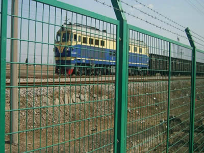 A train is passing through the railway with barb wire fence.