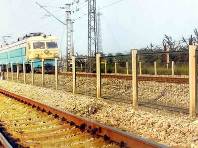 A train is passing through the railway that has welded wire railway fence between tracks.