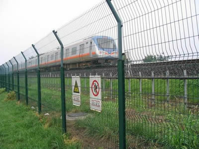 A train is passing through the railway with welded wire railway fence.