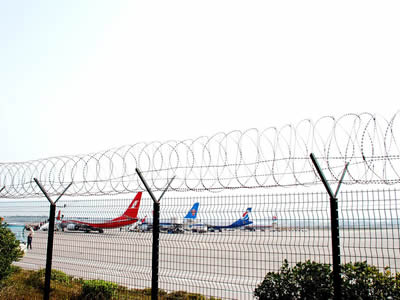 Several planes are parking on parking apron with welded wire fence.